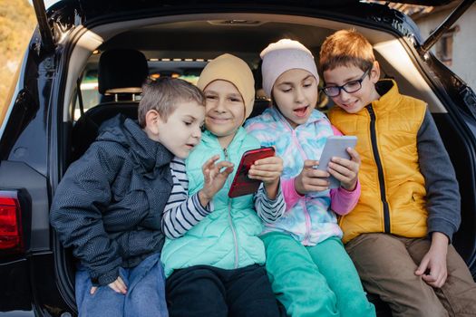 Children sitting on the car truck with smartphones and have fun