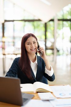 Asian businesswoman using the phone to contact a business partner.