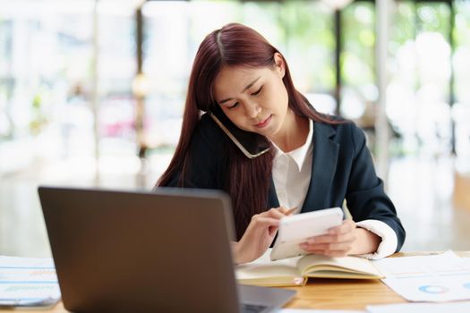 Asian businesswoman using the phone to contact a business partner.