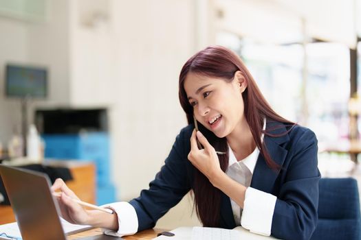 Asian businesswoman using the phone to contact a business partner.