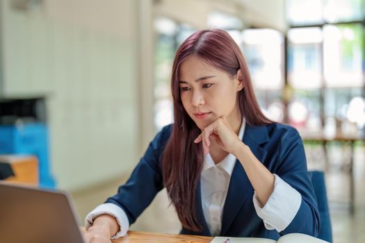 cheerful Asian celebrating her victory online with her laptop.