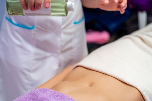 Top view of hands massaging female abdomen.Therapist applying pressure on belly. Woman receiving massage at spa salon.