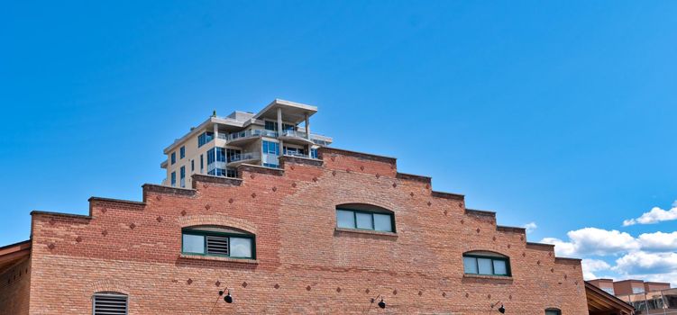 Brick wall of historic building with modern building on the back and blue sky background