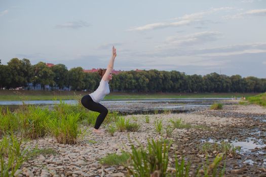 Yoga classes in nature. Young woman does yoga on rocks, near a river flows