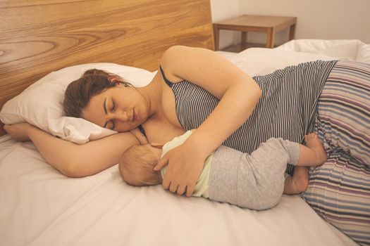 Mother and newborn baby sleep in the bed together