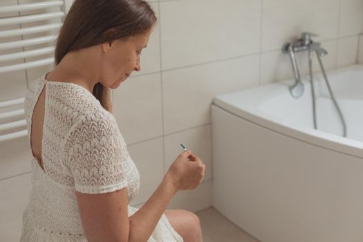 Worried middle age woman with pregnancy test in restroom
