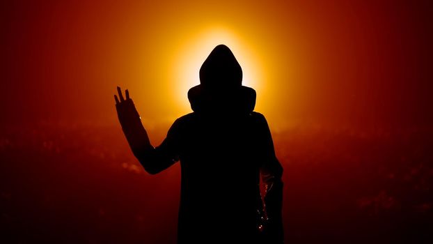 Silhouette of alien waving hand - hello on orange background. Humanoid on extraterrestrial planet. UFO, fantasy, futuristic, fiction concept. High quality photo