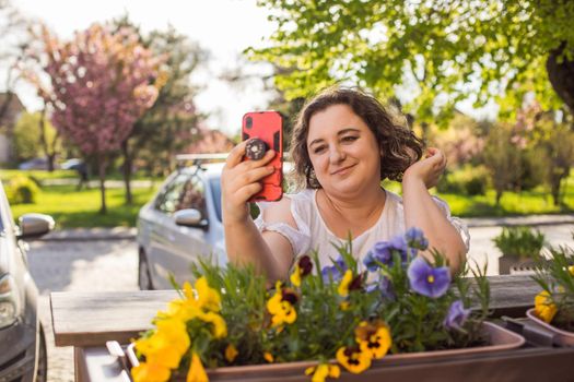 Smiling woman at outdoors cafe using mobile and having video call.