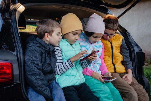 Children sitting on the car truck with smartphones and have fun