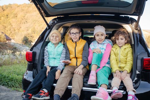 Group of children sitting in hatchback car with mountain background