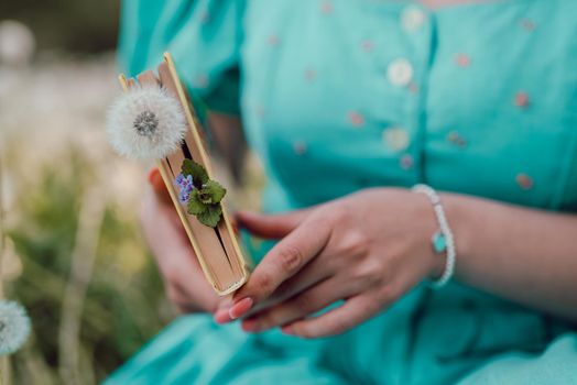 Hands of woman turns over pages of old paper book. Lady in retro or vintage dress reading interesting novel while sitting on nature. Atmospheric scene. Education, science, university concept. photo