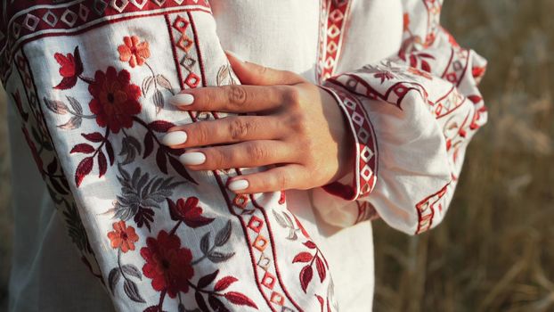 Ukrainian woman demonstrating beautiful details of embroidery ornament on vyshyvanka shirt. National costume - embroidered shirt, texture, design, folk, handmade craft needlework. High quality photo