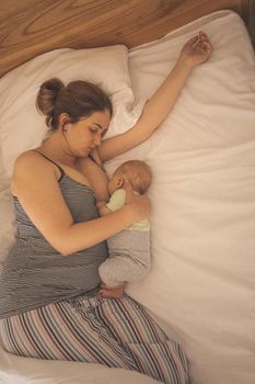 Mother and newborn baby sleep in the bed together