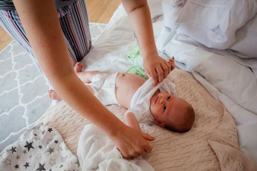 Woman interacting with her son before changing clothes. Baby lying on bed