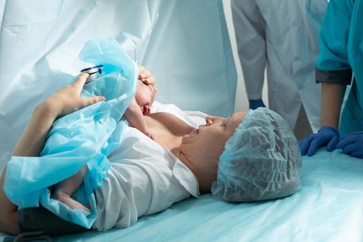 Mother holds newborn baby in hospital, seconds after birth.