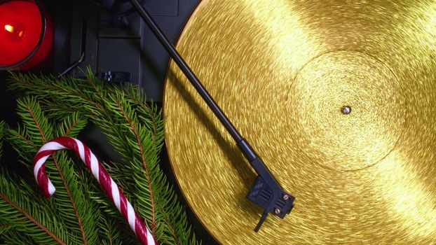 Fortuna gold, movie of retro-styled record player spinning golden vinyl. Cinemagraph. Christmas concept - spruce branch, lollipop and candle. Analog audio equipment, sound concept. High quality photo