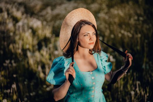 Young stylish woman in vintage dress and straw hat alone on nature in countryside. Carefree lifestyle, romantic girl. Retro fashionista like from novel. High quality photo