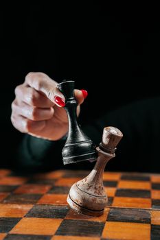 Woman player playing board intelligence game - wooden chess. Lady wins round with an opponent. Victory over enemy, power concept. Board strategy, success business, old vintage pieces. High photo