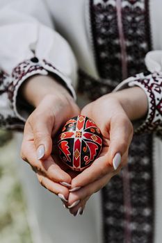 Ukrainian woman holding in hands Easter egg. Beautiful geometric slavic decoration. Lady in embroidery vyshyvanka dress. High quality photo