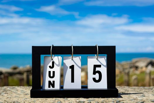 Jun 15 calendar date text on wooden frame with blurred background of ocean. Calendar date concept.