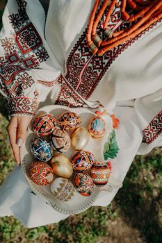 Ukrainian woman holding in hands Easter eggs. Beautiful geometric slavic decoration. Lady in embroidery vyshyvanka dress. High quality photo