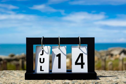 Jul 14 calendar date text on wooden frame with blurred background of ocean. Calendar date concept.