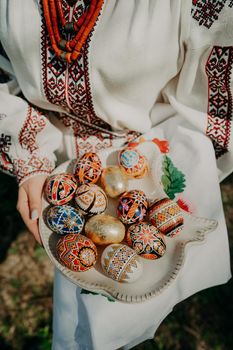 Ukrainian woman holding in hands Easter eggs. Beautiful geometric slavic decoration. Lady in embroidery vyshyvanka dress. High quality photo