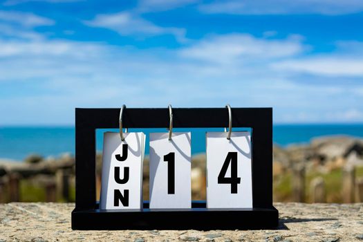 Jun 14 calendar date text on wooden frame with blurred background of ocean. Calendar date concept.