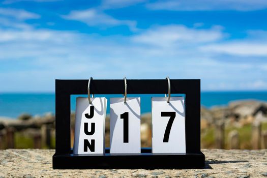 Jun 17 calendar date text on wooden frame with blurred background of ocean. Calendar date concept.