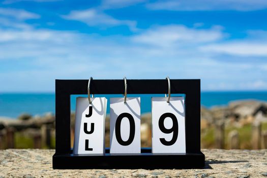 Jul 09 calendar date text on wooden frame with blurred background of ocean. Calendar date concept.