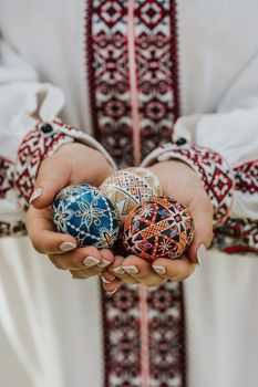 Ukrainian woman holding in hands Easter eggs. Beautiful geometric slavic decoration. Lady in embroidery vyshyvanka dress. High quality photo