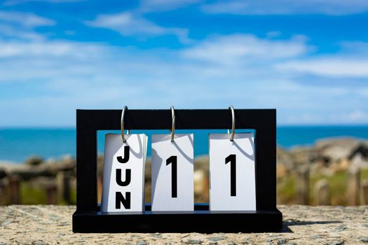 Jun 11 calendar date text on wooden frame with blurred background of ocean. Calendar date concept.