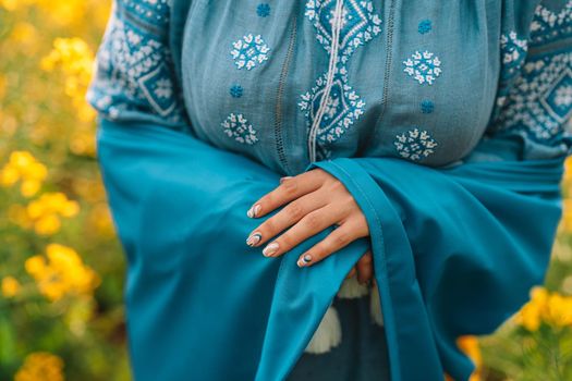 Ukrainian woman wrapped in national flag in canola field. Lady in vyshyvanka. Stand with Ukraine, freedom, patriot symbol, democracy victory in war. High quality photo