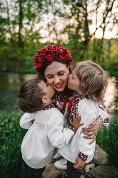 Little ukrainian boys kissing mother on cheeks. Happy family in traditional embroidery vyshyvanka shirts. Ukraine, brothers, sons, freedom, national costume. High quality photo