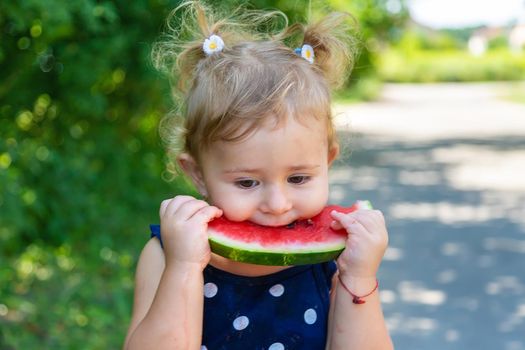 A child eats watermelon in the park. Selective focus. Kid.