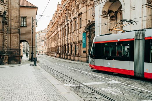 Prague, Czech Republic - July 2022. Modern tram on beautiful cozy street in old town. Urban public transport. Amazing european architecture, historical facades of traditional buildings. High quality