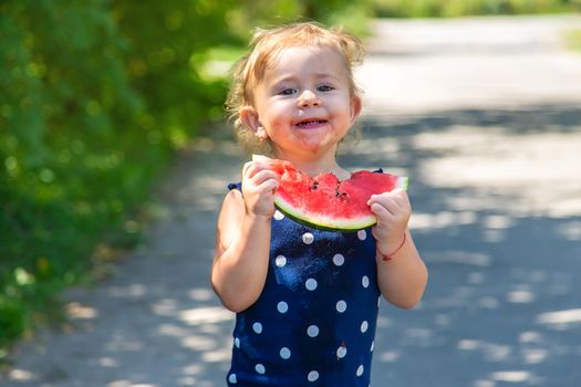 A child eats watermelon in the park. Selective focus. Kid.