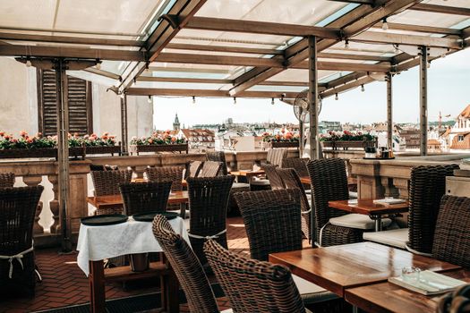 Beautiful terrace of restaurant in old european city on roof of building. View from high to down town. Rattan furniture. High quality photo