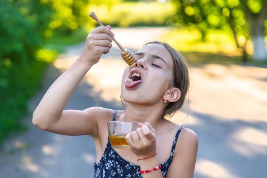 A child eats honey in the park. Selective focus. Kid.