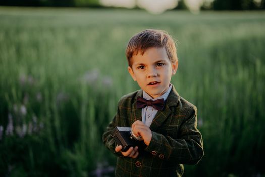 Handsome little boy with vintage retro camera. Kid as young photographer studying to take pictures. Hipster festive costume. Child, son, hobby, holiday concept. High quality photo
