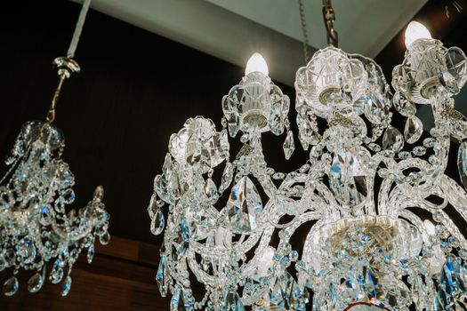 Beautiful czech crystal chandeliers on ceiling in dark night. Glass crystals hanging on vintage chandelier. High quality photo