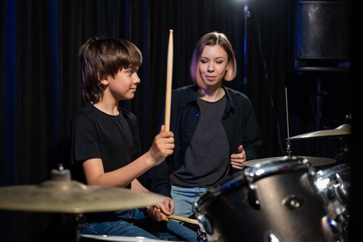 Young woman teaching boy to play drums