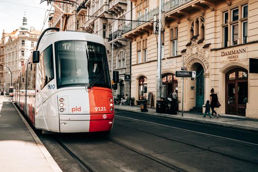 Prague, Czech Republic - July 2022. Modern tram on beautiful cozy street in old town. Urban public transport. Amazing european architecture, historical facades of traditional buildings. High quality