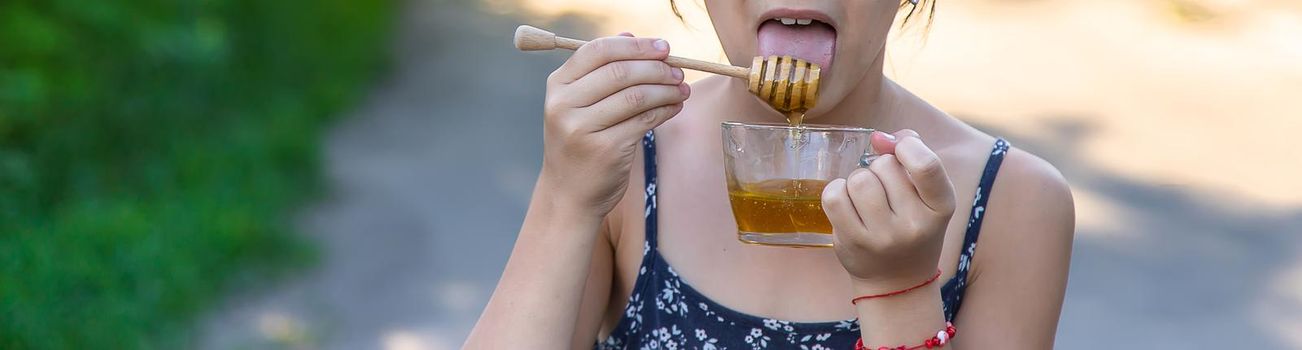 A child eats honey in the park. Selective focus. Kid.