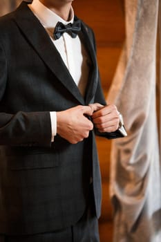 Stylish man groom buttoning a button on his jacket