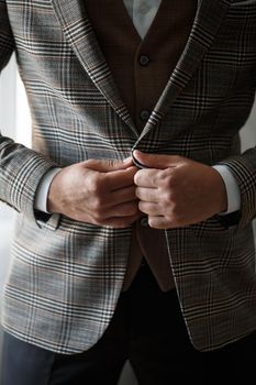 Stylish man groom buttoning a button on his jacket