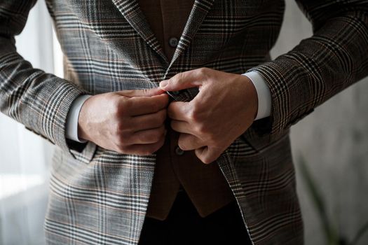 Stylish man groom buttoning a button on his jacket