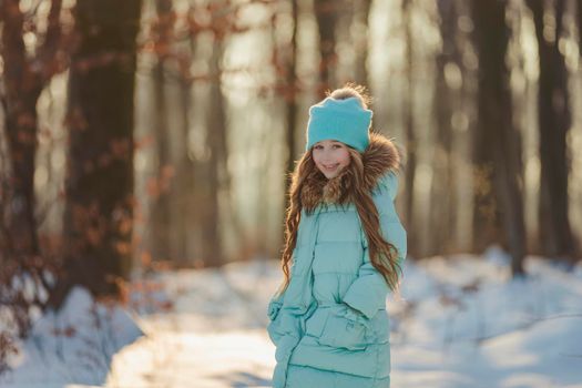 little girl in a winter forest and turquoise-colored clothes