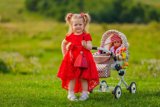 girl playing with a doll in a stroller in nature