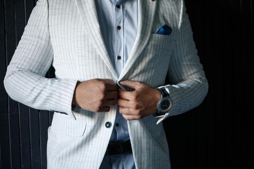 Stylish man groom buttoning a button on his jacket